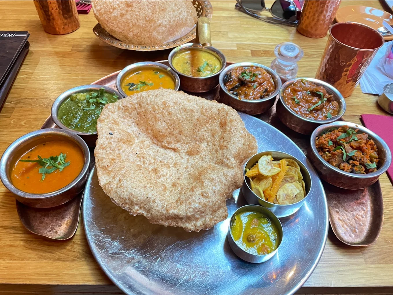 A Kerala thali with a large papadum and small copper bowls of curries