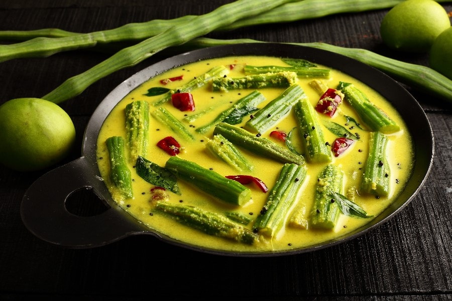 Okra in a turmeric and coconut curry in a black pan with dried chillies and lime
